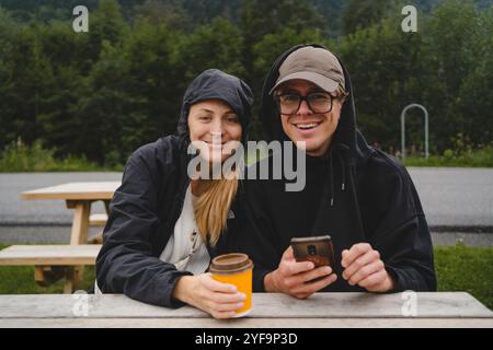 Portrait of smiling young couple sitting at park bench Stock Photo