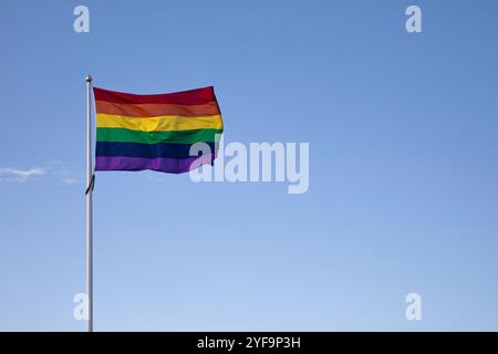 Low angle view of rainbow flag against blue sky Stock Photo