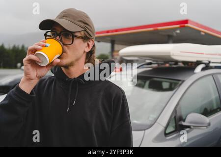 Handsome young man drinking coffee by car Stock Photo