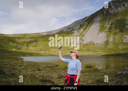 Young woman taking selfie while hiking on mountain Stock Photo
