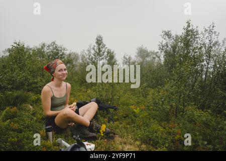 Portrait of smiling young woman eating snacks while sitting amidst plants Stock Photo