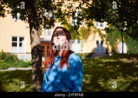 Smiling redhead woman standing at park Stock Photo