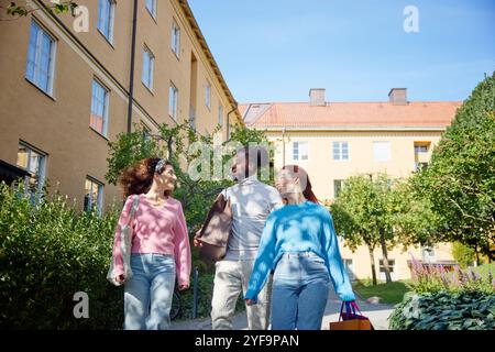 Multiracial male and female friends talking while walking in front of building Stock Photo