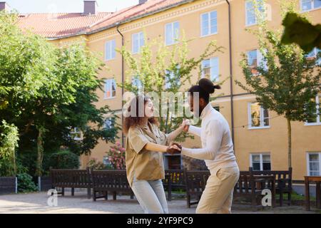Multiracial couple practicing salsa dance in building back yard Stock Photo