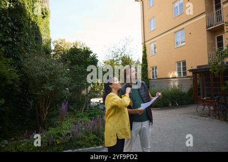 Male and female architects examining residential building while standing on footpath Stock Photo