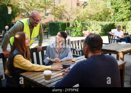 Happy male and female architects discussing with couple sitting on bench in garden Stock Photo