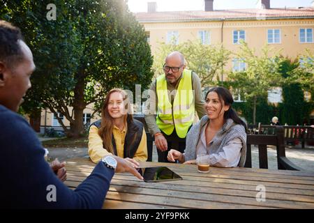 Female and male architects discussing with couple sitting on bench in garden Stock Photo