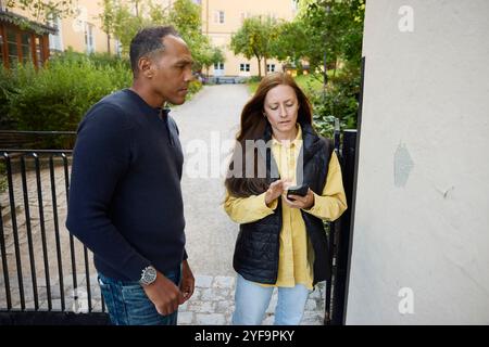 Mature man with female building inspector using smart phone while standing near wall Stock Photo
