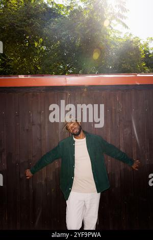 Fashionable young man standing against brown wall during sunny day Stock Photo