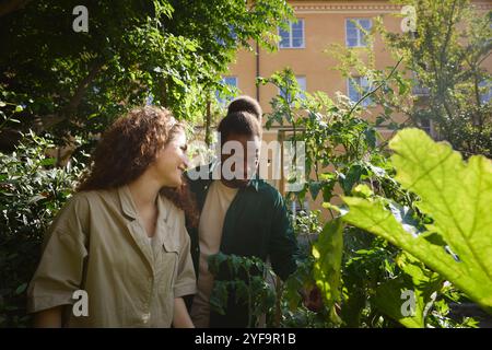 Multiracial friends standing amidst plants in public park Stock Photo