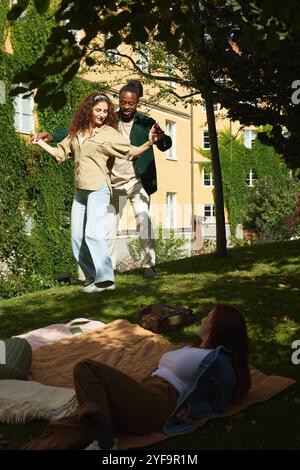 Couple dancing while female friend looking at them in park Stock Photo
