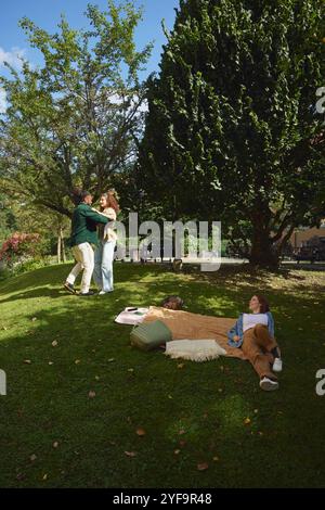 Young woman looking at couple dancing at park Stock Photo