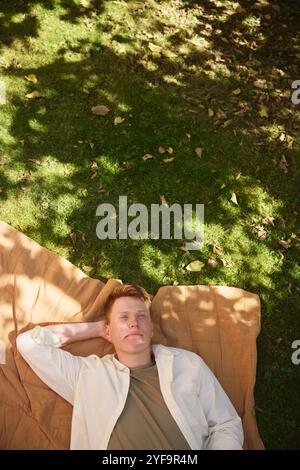 High angle view of thoughtful young man resting on mat in park Stock Photo