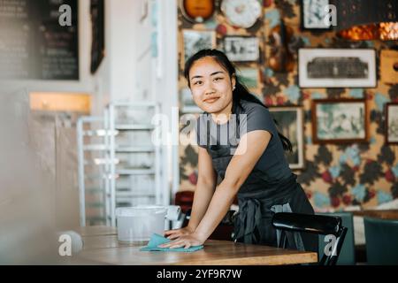 Portrait of young waitress cleaning table in cafe Stock Photo