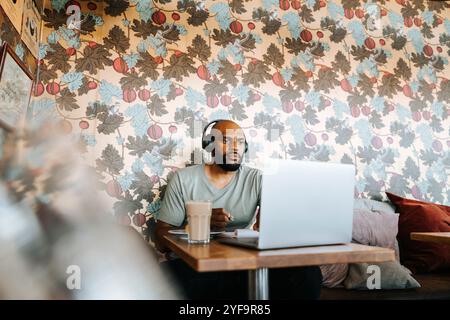 Serious man wearing headphones while using laptop at cafe Stock Photo