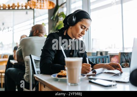 Young woman freelancing while sitting in cafe Stock Photo