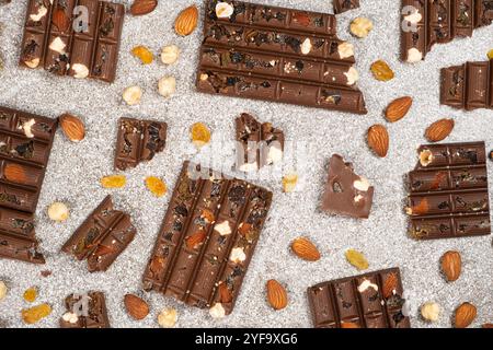 Broken chocolate pieces with nuts and raisins on a stone background top view Stock Photo