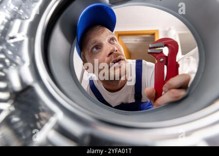 washing machine repair service. repairman looking inside drum Stock Photo