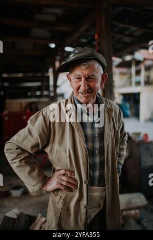 Old man in working clothes standing in his barn. Stock Photo