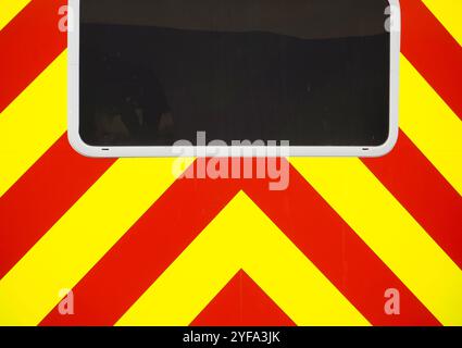 Red and yellow chevron pattern danger or warning stripes on rear of vehicle with blacked out window. Horizontal or landscape format. Stock Photo