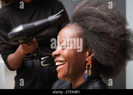 Hairdresser using a hairdryer to prepare afro hair for crochet braids Stock Photo