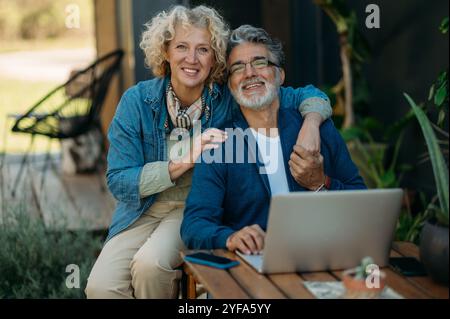 Middle-age couple smiling confident using laptop in the garden. Stock Photo