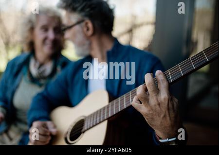 Man playing an accoustic guitar with his woman in background. Stock Photo