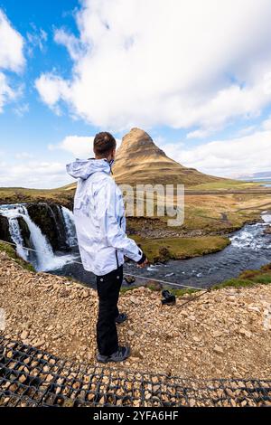 Man standing in front of Kirkjufell mountain and Kirkjufellsfoss waterfall on the Snaefellsnes Peninsula in Iceland Stock Photo
