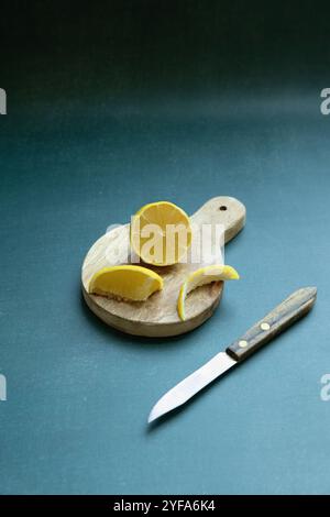 sliced lemon on rustic cutting board against green background Stock Photo