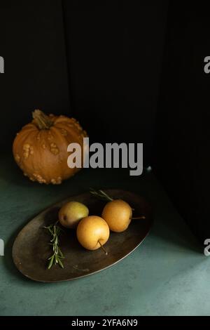 Rustic still life with pumpkin, pears, and rosemary on a dark tray Stock Photo