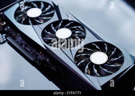Close-up of high-performance graphics card with three cooling fans on dark background. Modern video card for gaming and advanced computing Stock Photo