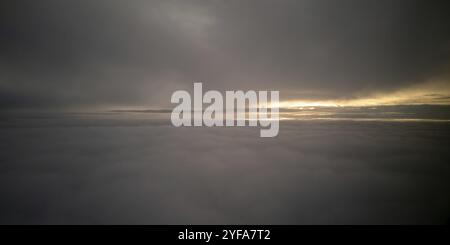 Bright sun rays light shining above dark cloudy sky. Sunset form airplane while flying Stock Photo