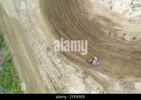 Drone aerial of a motocross race on a dirt curvy sport track. Aerial view of high-speed racing. Athletes in action Stock Photo