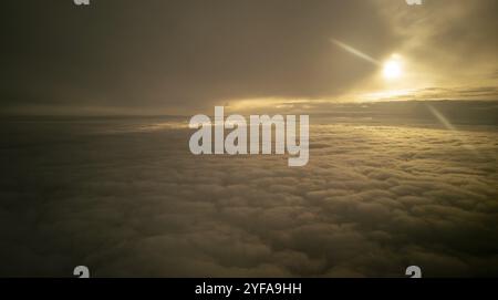 Bright sun rays light shining through dark clouds over mountain at sunset. Dramatic sky in winter Stock Photo