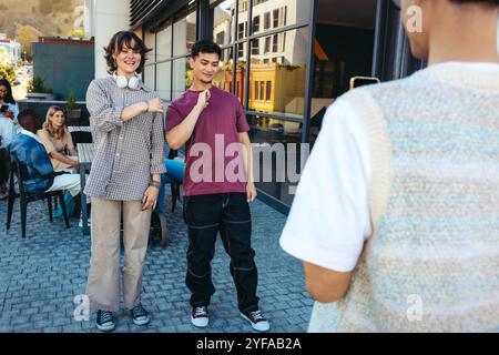 Young students enjoying a dance practice session, capturing fun moments for social media. Group of friends rehearsing outdoors in a lively, casual urb Stock Photo