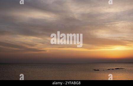 Dramatic beautiful sunset in the coast. Orange dramatic colours on cloudy sky. End of day. Sun on the horizon Stock Photo
