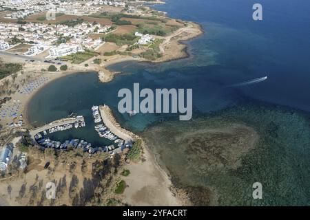 Aerial drone view of fishing harbour and sandy beach. Agia Triada people swimming and fishing boats moored at the harbor. Protaras Paralimni Cyprus Stock Photo