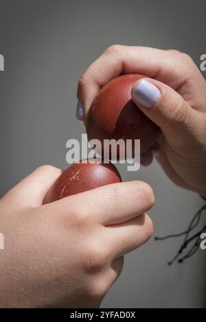 Two hands holding red easter eggs trying to crack the eggs to find the winner. Traditional easter competition Stock Photo