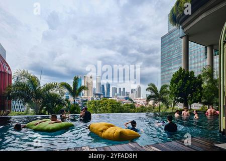 Singapore - August 16, 2024: Park Royal Collection Pickering Hotel infinity pool with tropical plants and colorful lodges Stock Photo