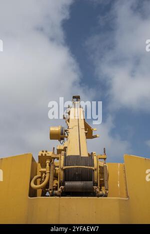 Details of a yellow industrial crane against blue cloud sky. Heave duty machinery for construction outdoor Stock Photo