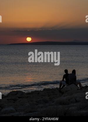 Silhouette of young couple enjoying beautiful sunset at the beach ...