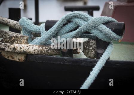 Twisted ship mooring strong rope for securing fishing boats tied on a metal pole. Security, safety fasten Stock Photo