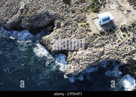 Drone aerial photograph of Cape Greco peninsula with Agioi Anargyroi christian church on the rocks. Turquoise ocean water Stock Photo