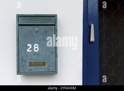 Old green metal letter box and house number on an a white wall Stock Photo