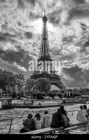 Tourists admire the Eiffel Tower from a boat cruising on the Seine River, Paris, France, in black and white Stock Photo