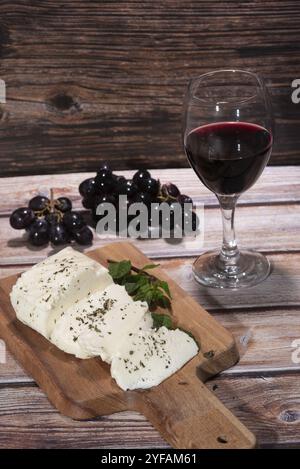 Traditional slices of cyprus halloumi cheese red wine and grapes on a table Stock Photo