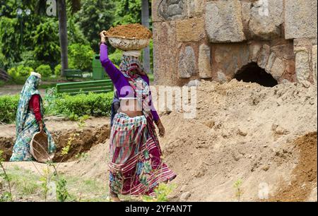 New Delhi, India, August 8 2018: Indian women working on construction industry outdoors carrying sand on head for building, Asia Stock Photo