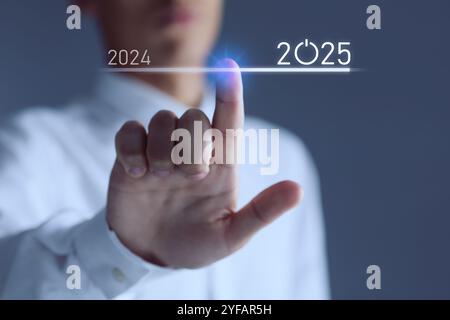 New year goals. Businessman touching line leading from 2024 to 2025 on virtual screen against dark background, closeup Stock Photo