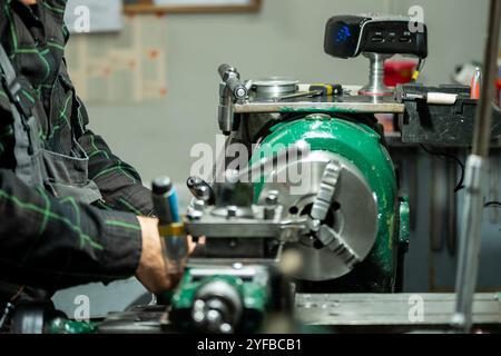 A worker operating a lathe machine, focusing on precise metalworking tasks in a workshop environment. Stock Photo