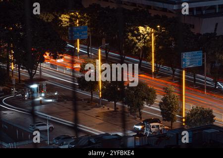Nighttime long-exposure of a busy city street, capturing light trails from moving vehicles and illuminated street lamps, showcasing the dynamic energy Stock Photo